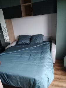 a bed with blue sheets and pillows in a bedroom at Grand studio cosy et lumineux in La Rochelle