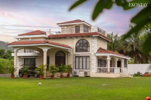 a large house with a green lawn in front of it at EKOSTAY - Casa Amado in Alibaug