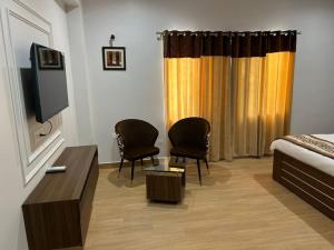 a room with a bed and two chairs and a tv at STARLIT Hotel, Ajmer in Madār +20 photos