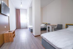 a hotel room with a bed and a desk and a table at Nura Hotel in Shymkent