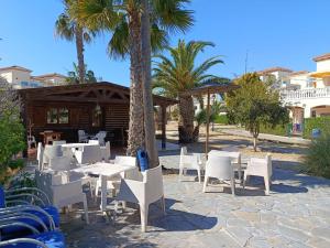 a patio with white tables and chairs and palm trees at Urbanización Torremar Natura in Vera
