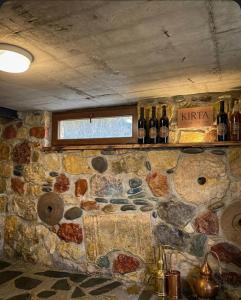 a room with a stone wall with bottles of wine at Kirta in Gordi