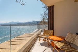 a balcony with chairs and a table and a view of the water at Beau Rivage Suites in Lóngos