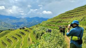 a person taking a picture of a hill with a camera at Indigenous homestay - Trek & Local Life in Mù Cang Chải