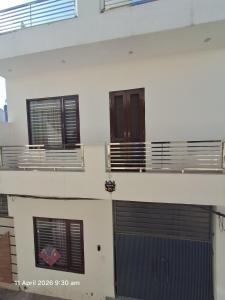a white building with two garage doors and windows at SG Homestay in Amritsar