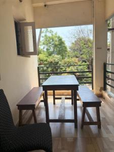 a table and benches in a room with a balcony at Serenity Beach House in Pondicherry