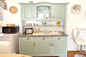 a kitchen with green cabinets and a microwave at Zach Waldglück in Groß Klessow