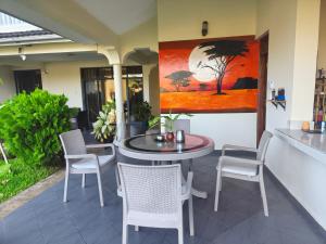 a patio with a table and chairs and a painting at Lisa Mari in Mombasa