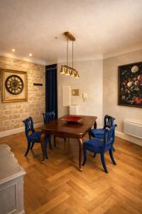 a dining room with a wooden table and blue chairs at La Salamandre - Un écrin médiéval pour vos souvenirs - Imaginez-vous, réveillé par le murmure de Sarlat, dans un appartement spacieux et chaleureux, au cœur de la Cité classée - 2 chambres - Une magie à vivre sans modération - Réservez dès maintenant ! in Sarlat-la-Canéda +15 photos