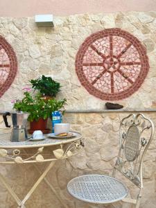 a table and a chair next to a stone wall at B&B Vicolo del Chiostro in Aci SantʼAntonio