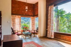 a living room with a large window and a table and chairs at Urvinkaan - An Estate Hotel Chikmagalur in Chikmagalur