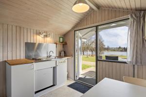 a kitchen with white appliances and a large window at Sorø Camping & Cottages in Sorø