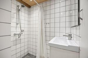 a white tiled bathroom with a sink and a shower at Sorø Camping & Cottages in Sorø +69 photos