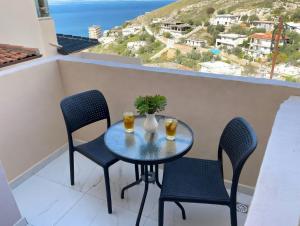 a table and chairs on a balcony with a view of the ocean at Kloen Sunset Villa in Sarandë