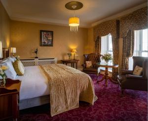 a hotel room with a large bed and a chair at Arbutus Hotel in Killarney