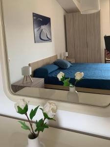 a mirror in a bedroom with a bed and flowers at Incanto dei sibillini- Piazza Perfetti 16 in Sarnano