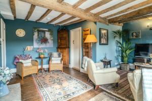 a living room with blue walls and wooden ceilings at 4 Crown Cottages in Moreton in Marsh