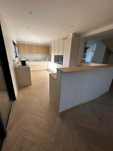 a large kitchen with white cabinets and a wooden floor at Villa ALDAKETA in Urrugne