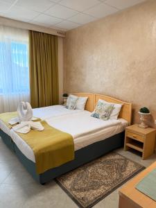 a bedroom with a large bed with a yellow blanket at Port Lake Hotel in Beloslav