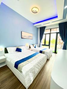 two beds in a bedroom with blue walls and windows at QV Manor - Homestay kề biển Bình Sơn in Phan Rang–Tháp Chàm