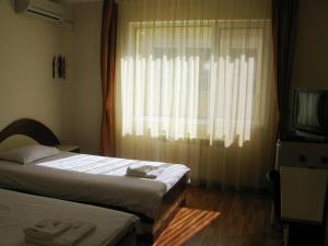 a bedroom with two beds and a window with a television at Hotel Nakra in Radnevo