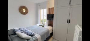 a white bedroom with a bed and a mirror at Apartament w Esteponie in Estepona