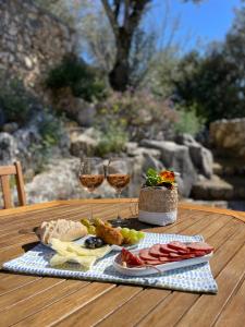 a table with a plate of food and two glasses of wine at Suite Pedra Oliveira - Piscine salée privée - Proche Coimbra - Centre Portugal in Ameixeira