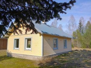a small yellow house sitting on top of a yard at Heinamaa Lodge with sauna in Lammasküla