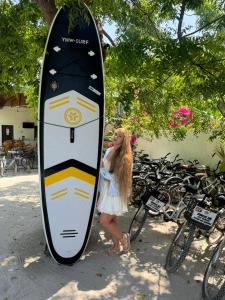 a young girl is standing next to a surfboard at Sunrise Inn in Thoddoo +56 photos