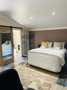 a bedroom with a large white bed and a mirror at Redem House in Modimolle