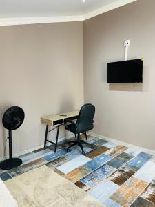 a desk and a chair in a room with a television at Redem House in Modimolle