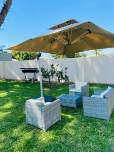 a group of chairs and an umbrella in the grass at Redem House in Modimolle