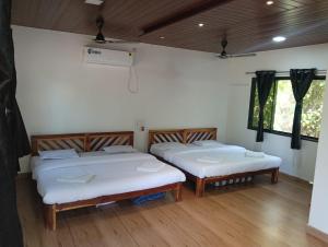 two beds in a room with wooden floors and windows at Awas Beach Stays in Avas