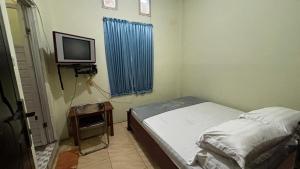 a small bedroom with a bed and a tv at Hotel SIDAPORE in Lamobuang