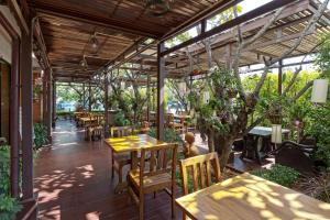 a restaurant with wooden tables and chairs and trees at Asia Hotels Group (Poonpetch Chiangmai) in Chiang Mai