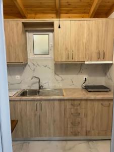 a kitchen with wooden cabinets and a sink at Kloen Sunset Villa in Sarandë +34 photos
