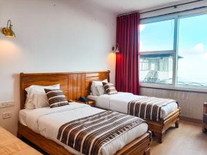 two beds in a room with a window at The Three Oaks Boutique Hotel in Mussoorie