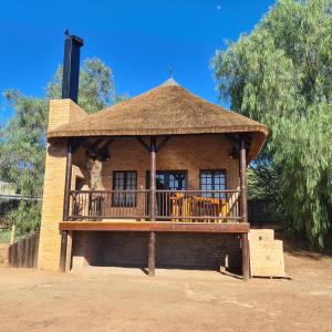 a building with a deck with chairs on it at DuckPond Lodge Cottage in Oudtshoorn