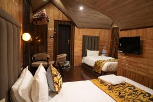 a hotel room with two beds and a flat screen tv at Green Inn in Pahalgām +10 photos