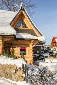 eine Blockhütte mit Schnee auf dem Dach in der Unterkunft udanypobyt Domki Przy Potoku in Zakopane