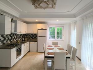 a kitchen with a table and white cabinets and a table and chairs at Amazonica MAGİC DREAM in Kemer