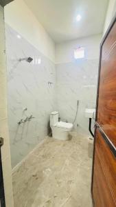 a white bathroom with a toilet and a sink at Hotal Shivaay inn in Barāgaon