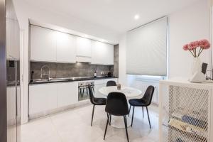 a kitchen with white cabinets and a table and chairs at La Scaletta 10 min from train station for Cinque Terre! in La Spezia