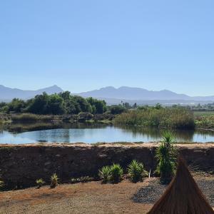 a body of water with trees and mountains in the background at DuckPond Lodge Cottage in Oudtshoorn