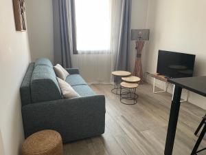 a living room with a blue couch and a table at Le S in Argelès-sur-Mer