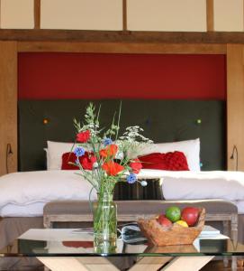 a vase of flowers on a table in front of a bed at Knelle Dower Studio in Northiam