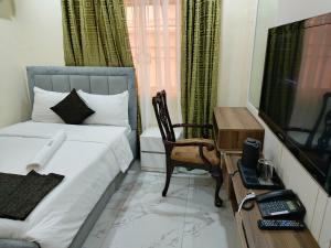 a bedroom with a bed and a chair and a television at Captain Residency Hotel in Lagos