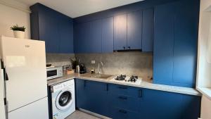 a kitchen with blue cabinets and a washing machine at Novus Luxury Apartment Free Parking in Craiova +5 photos