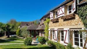 a stone house with red and white windows and ivy at Les Maisons de Mélody in Houlbec-Cocherel