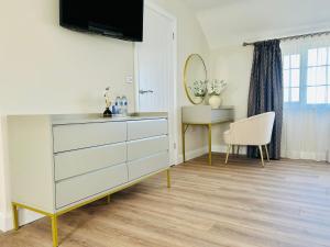 a room with a dresser and a table and a mirror at Brackengarth House in Purdysburn